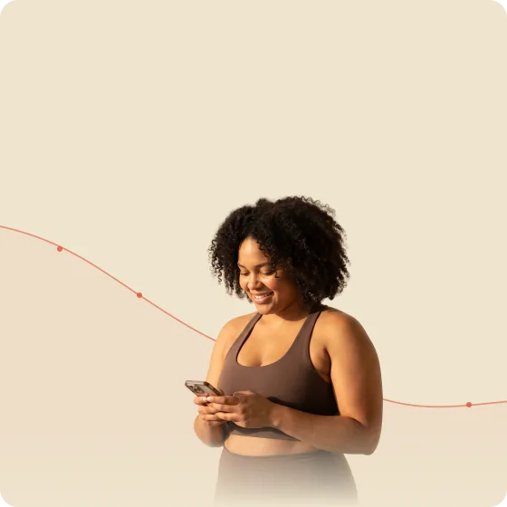 A woman smiling at her phone in front of a downward weight-trend line