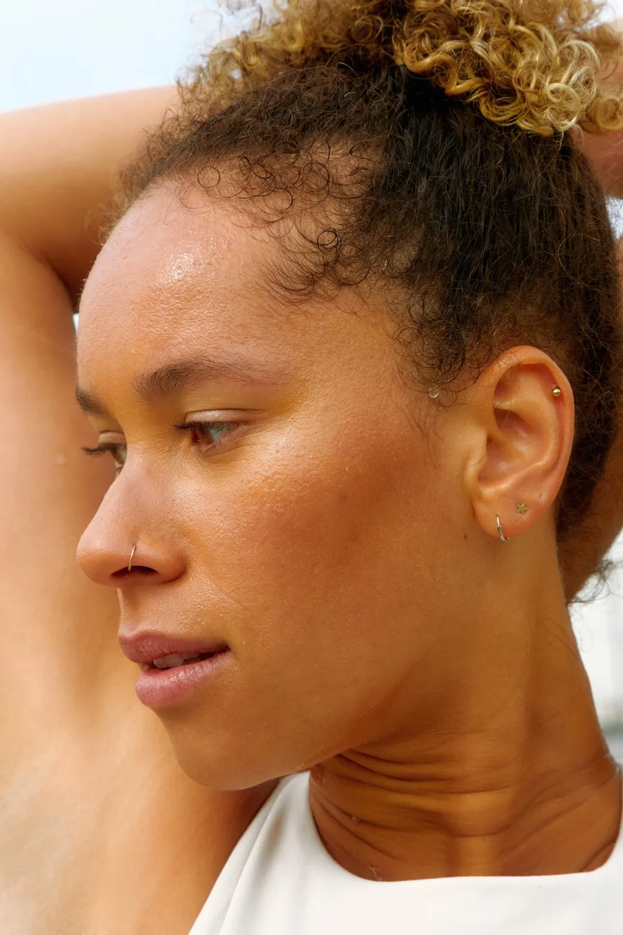 A woman in soft light resting her head thoughtfully on her shoulder